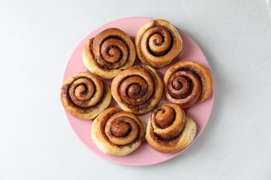 Many tasty cinnamon rolls on white table, top view