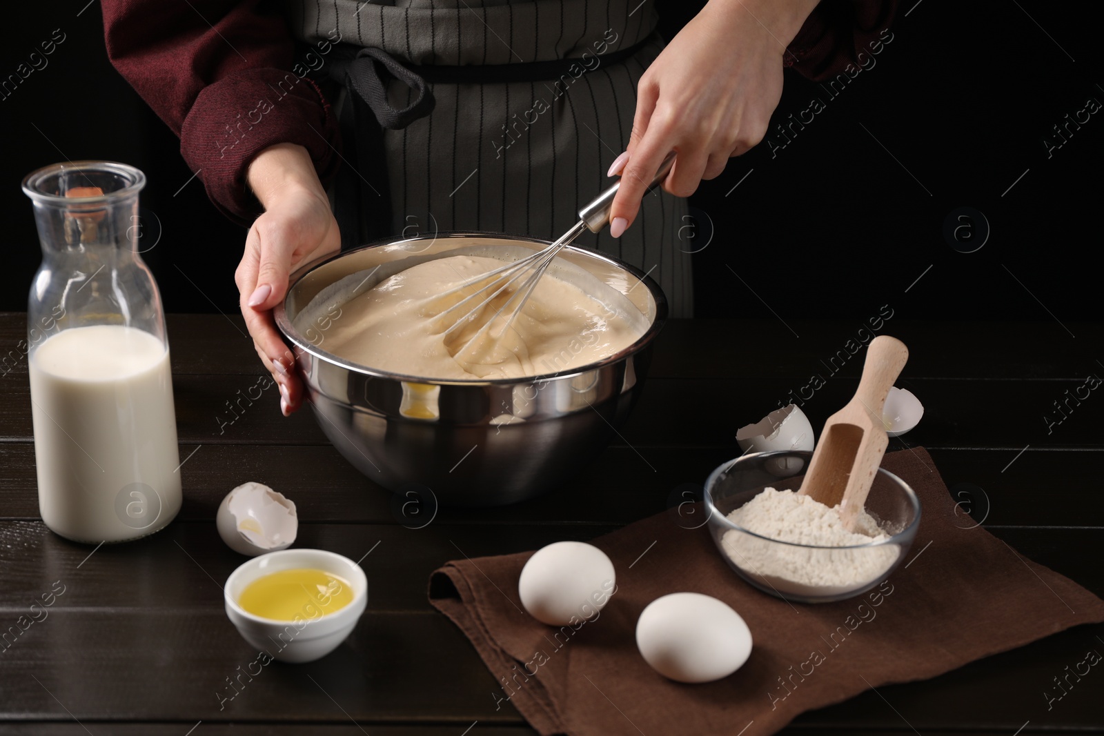 Photo of Woman making dough with whisk in bowl at table, closeup