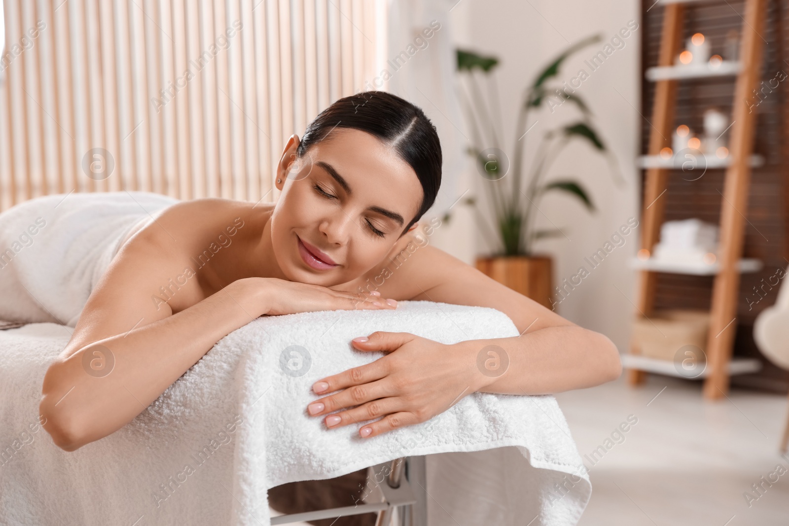 Photo of Young woman resting on massage couch in spa salon