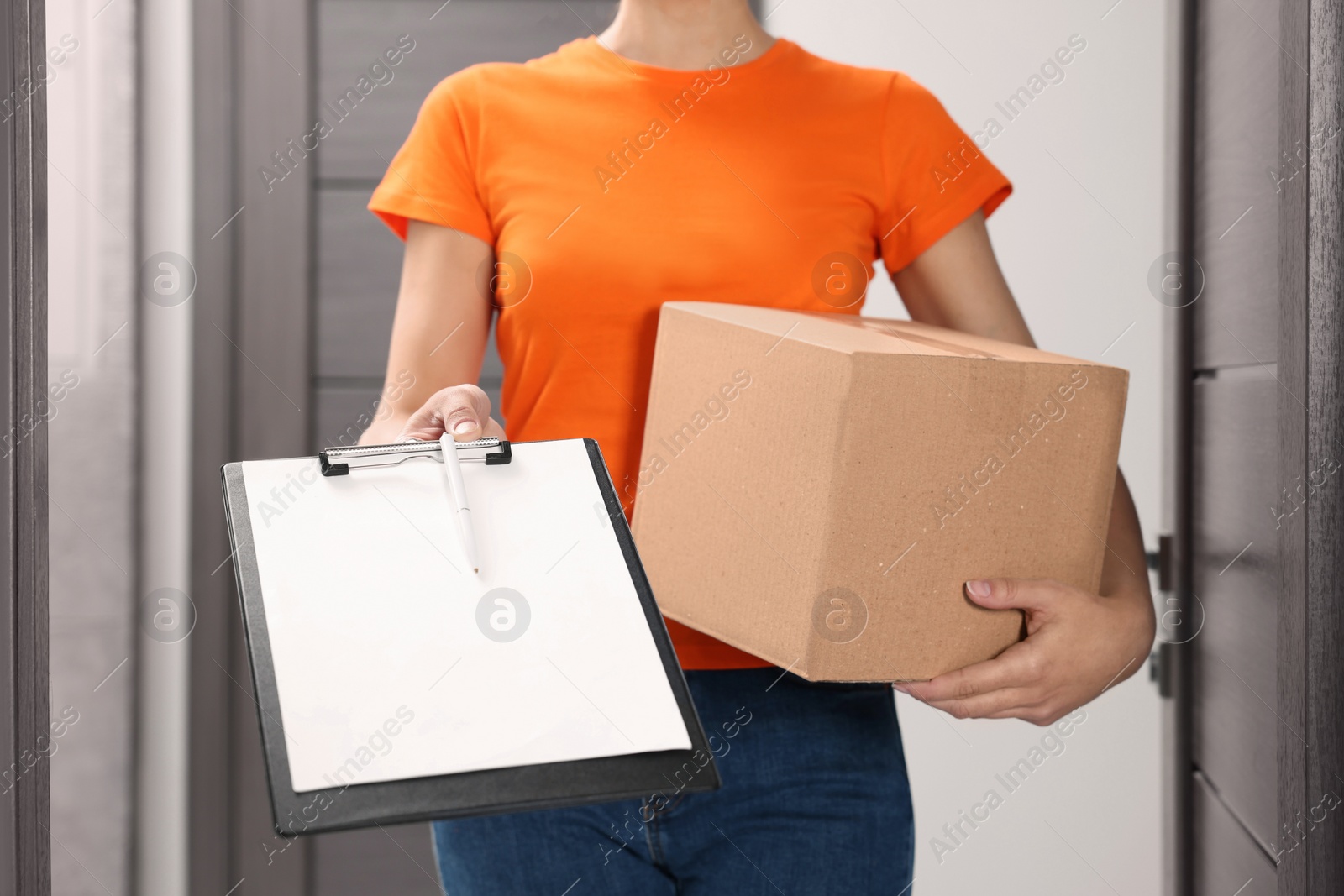 Photo of Courier holding parcel and clipboard indoors, closeup