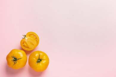 Photo of Cut and whole ripe yellow tomatoes on pink background, flat lay. Space for text