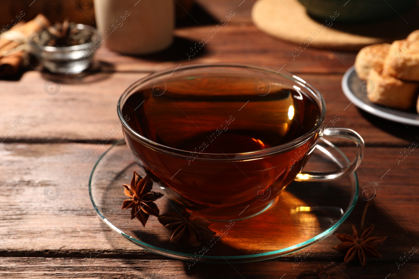 Photo of Aromatic tea with anise stars on wooden table, closeup