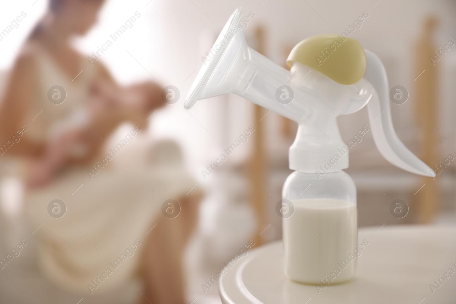 Photo of Mother and little baby indoors, focus on table with breast pump