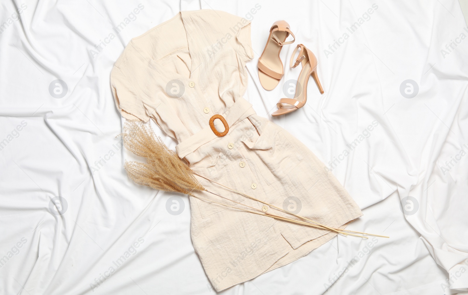 Photo of Stylish dress, shoes and spikelets on white fabric, flat lay