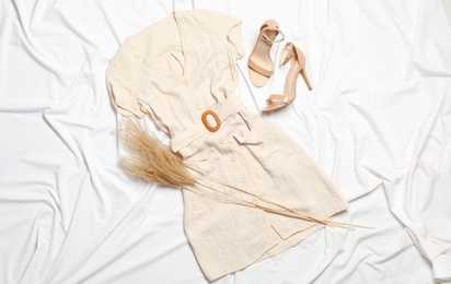 Stylish dress, shoes and spikelets on white fabric, flat lay