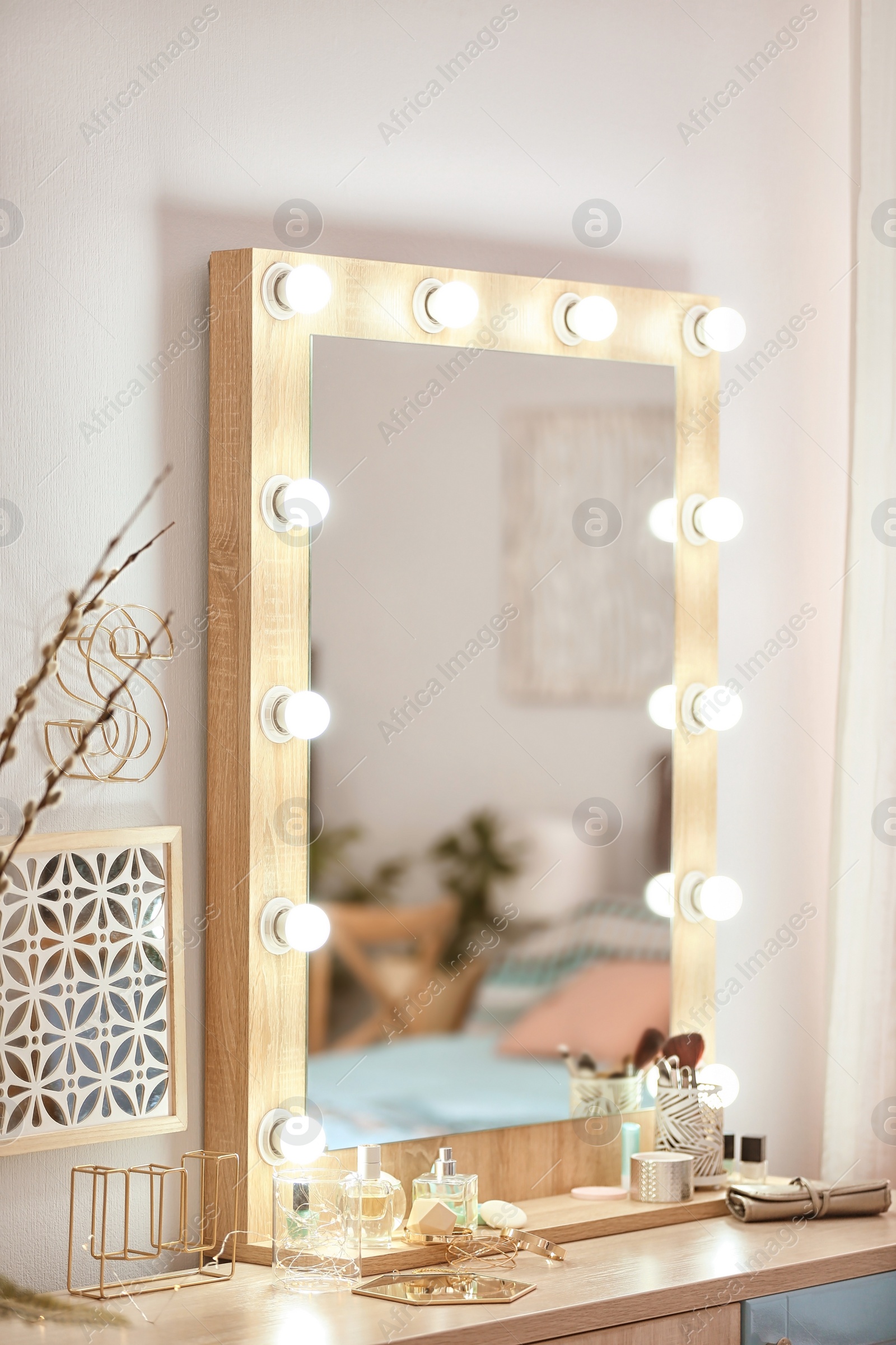 Photo of Mirror with light bulbs and cosmetic products on dressing table indoors