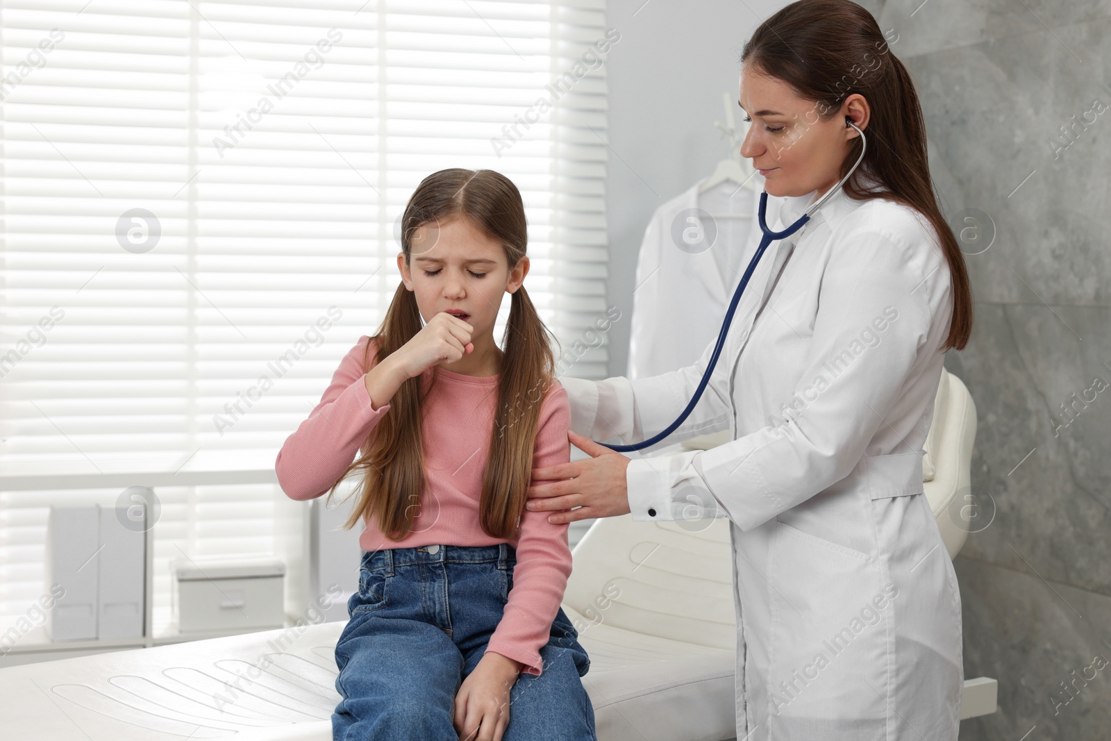 Photo of Doctor examining coughing girl in hospital. Cold symptoms