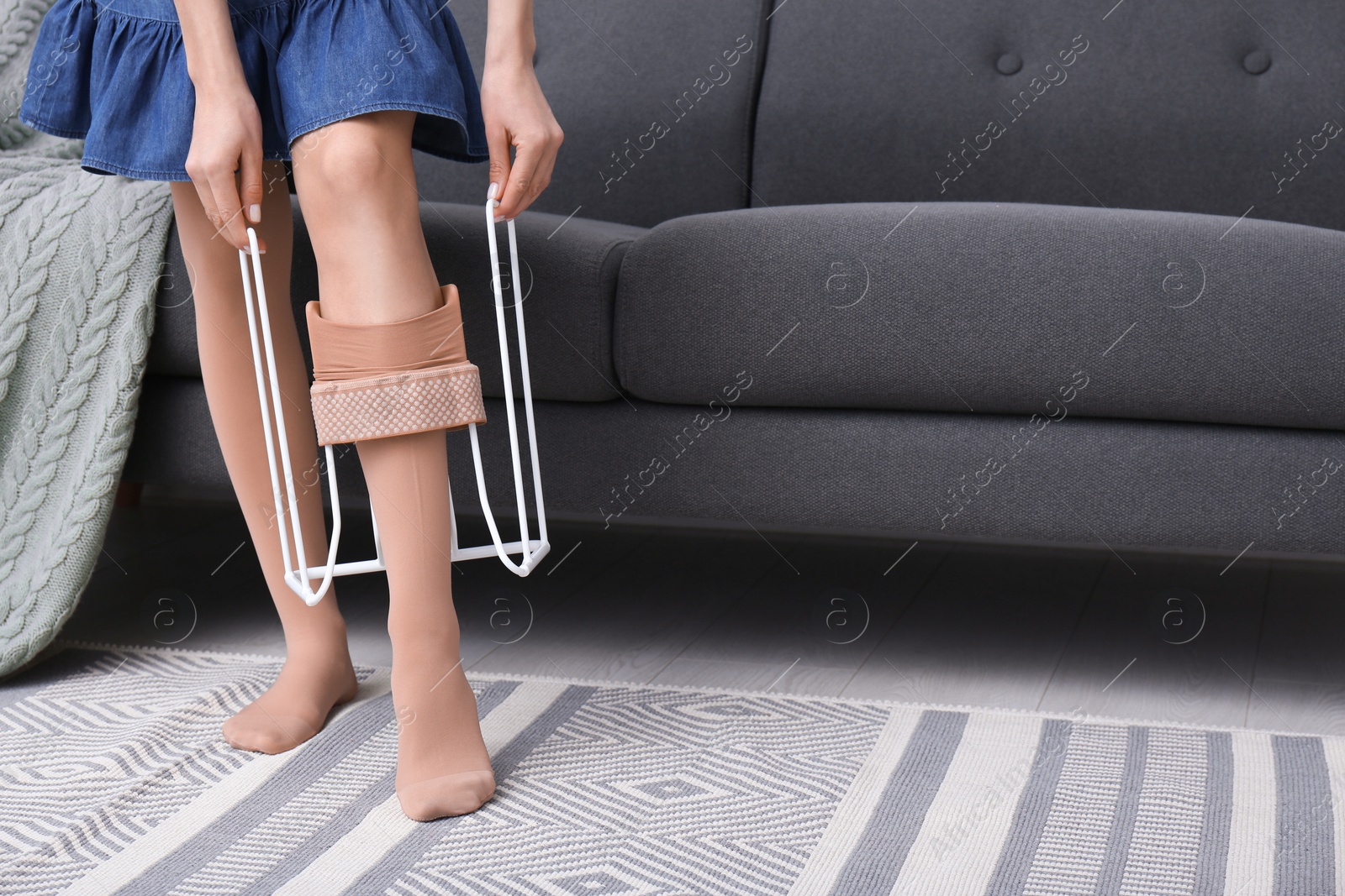 Photo of Woman wearing compression tights with donner on sofa indoors, closeup. Space for text