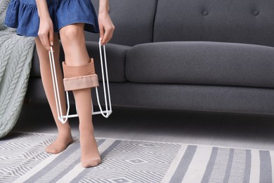 Woman wearing compression tights with donner on sofa indoors, closeup. Space for text