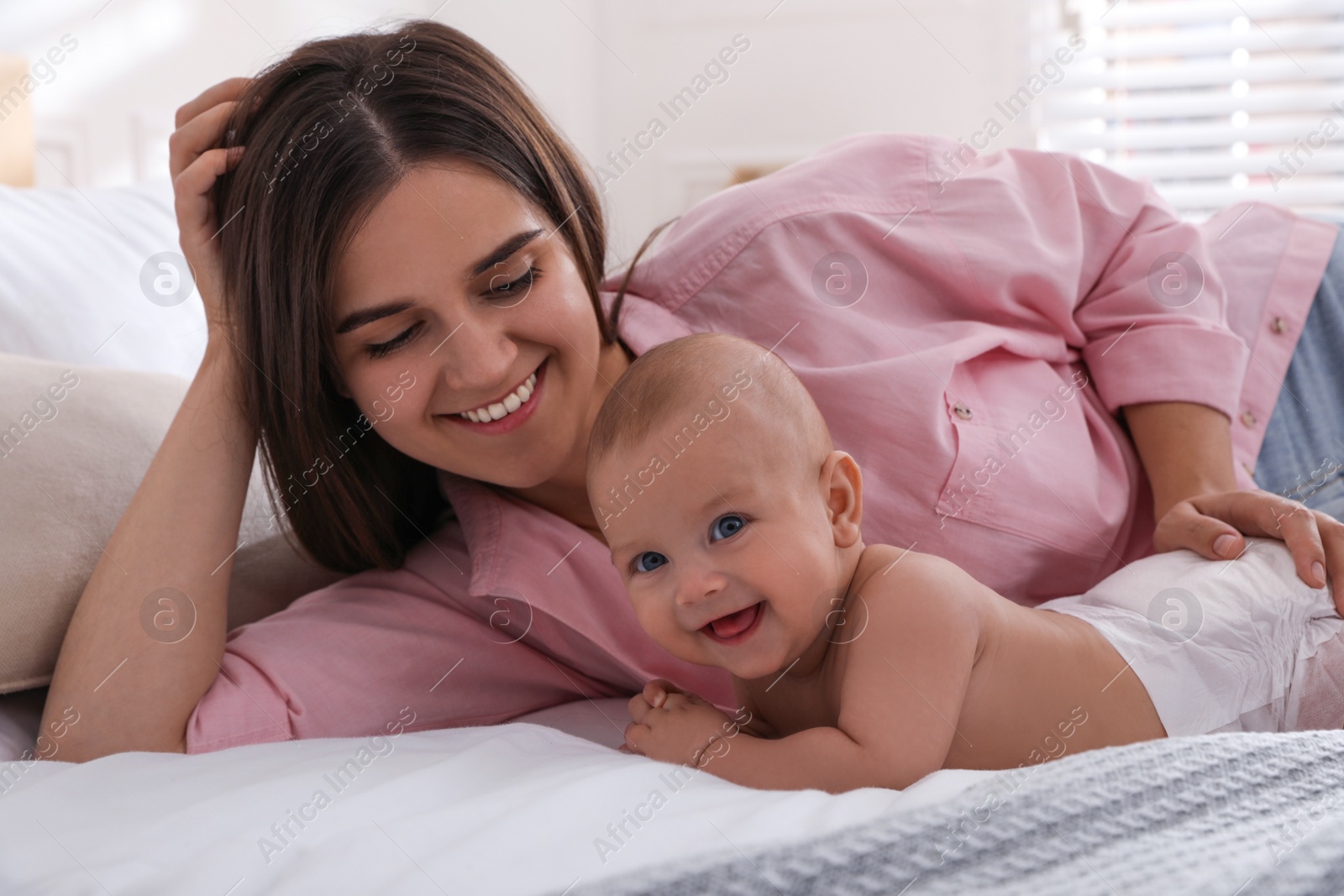 Photo of Mother with her cute baby on bed at home