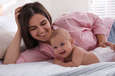 Mother with her cute baby on bed at home