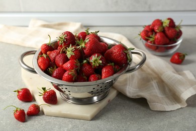 Photo of Metal colander with fresh strawberries on grey countertop