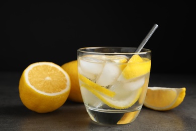 Soda water with lemon slices and ice cubes on grey table