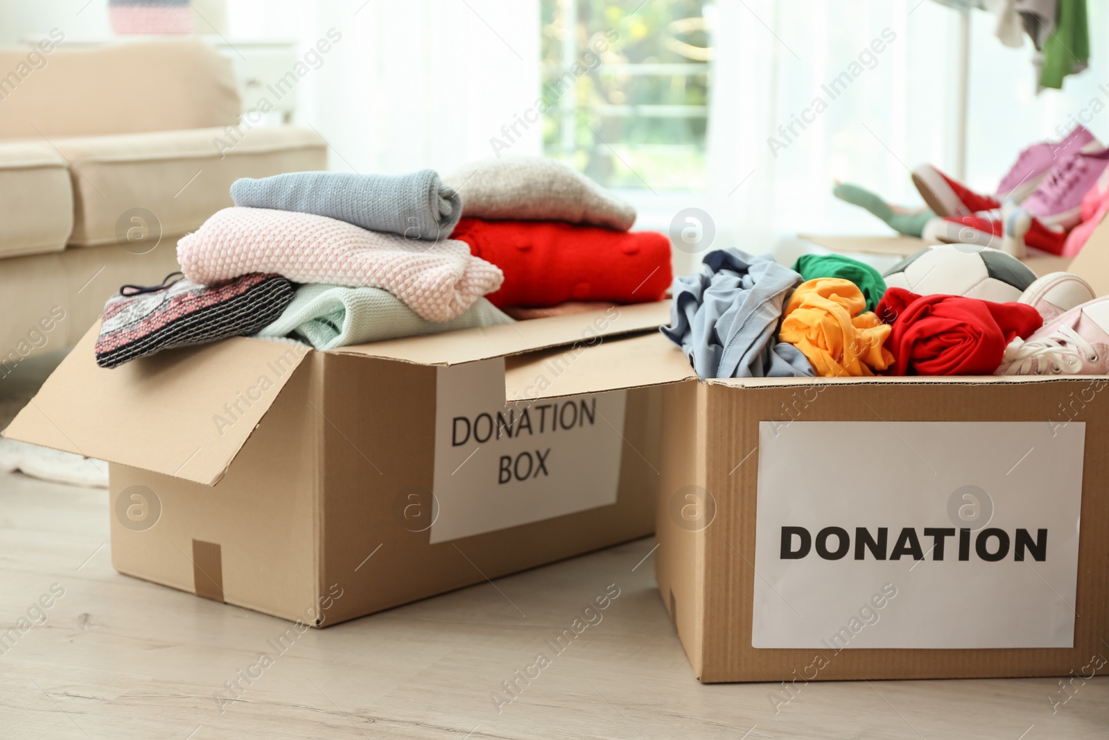 Photo of Donation boxes with clothes on floor indoors