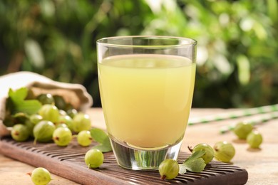 Tasty gooseberry juice and fresh berries on wooden table