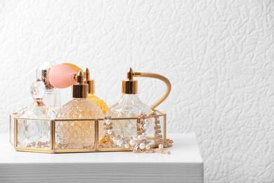 Photo of Tray with perfume bottles and jewellery on table against white background