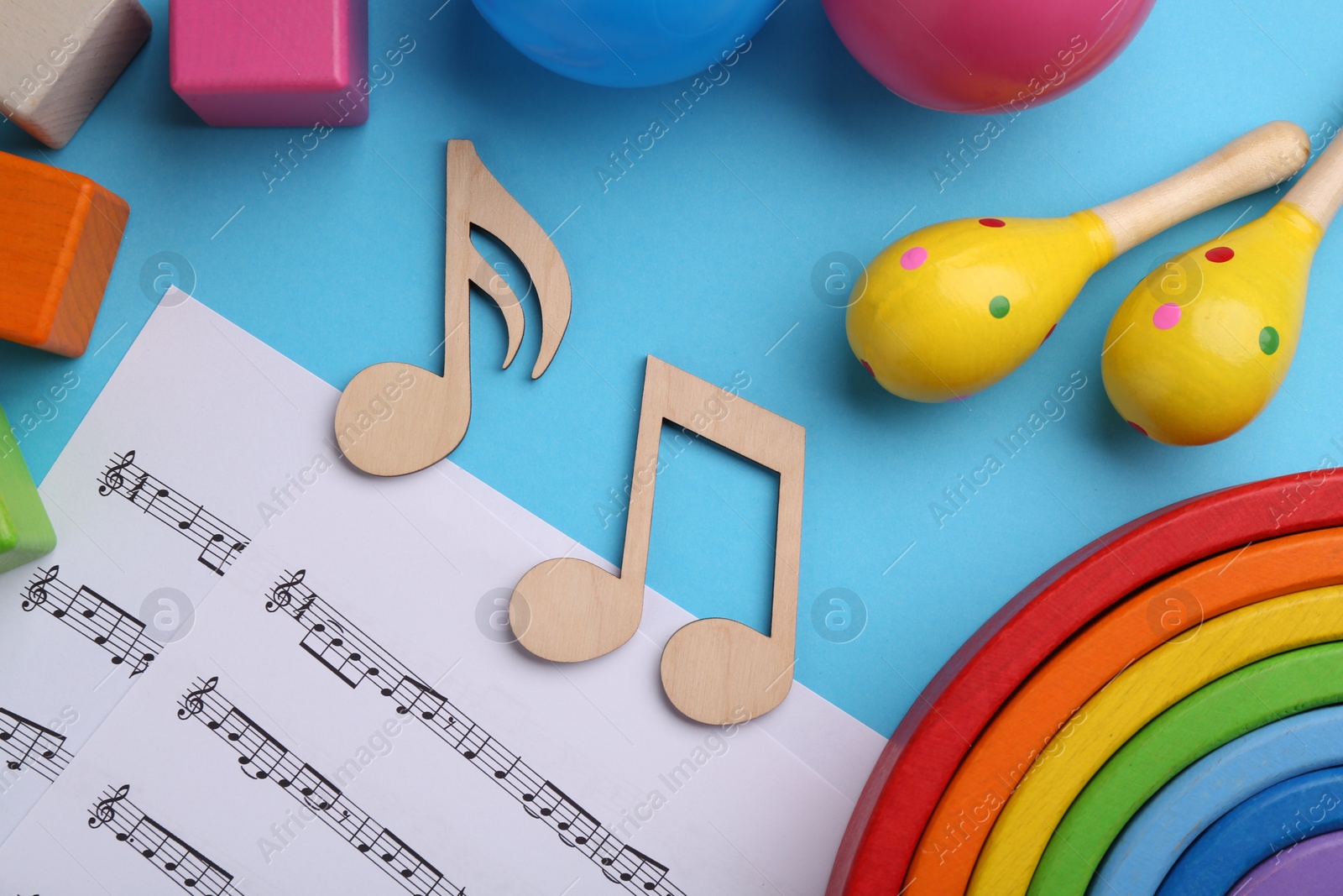 Photo of Tools for creating baby songs. Flat lay composition with wooden notes and maracas on light blue background