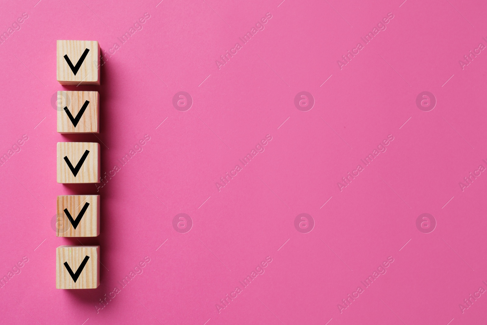 Image of Wooden cubes with check marks on pink background, top view. Space for text