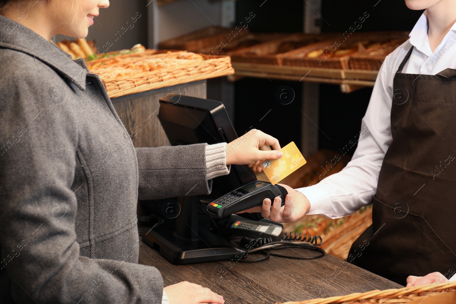 Photo of Woman with credit card using payment terminal at shop