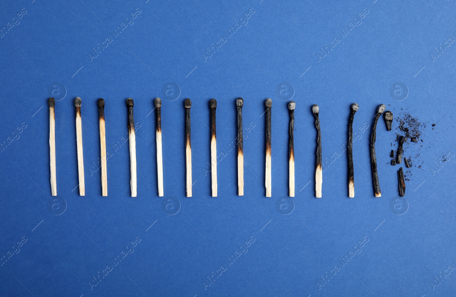 Photo of Different stages of burnt matches on blue background, flat lay