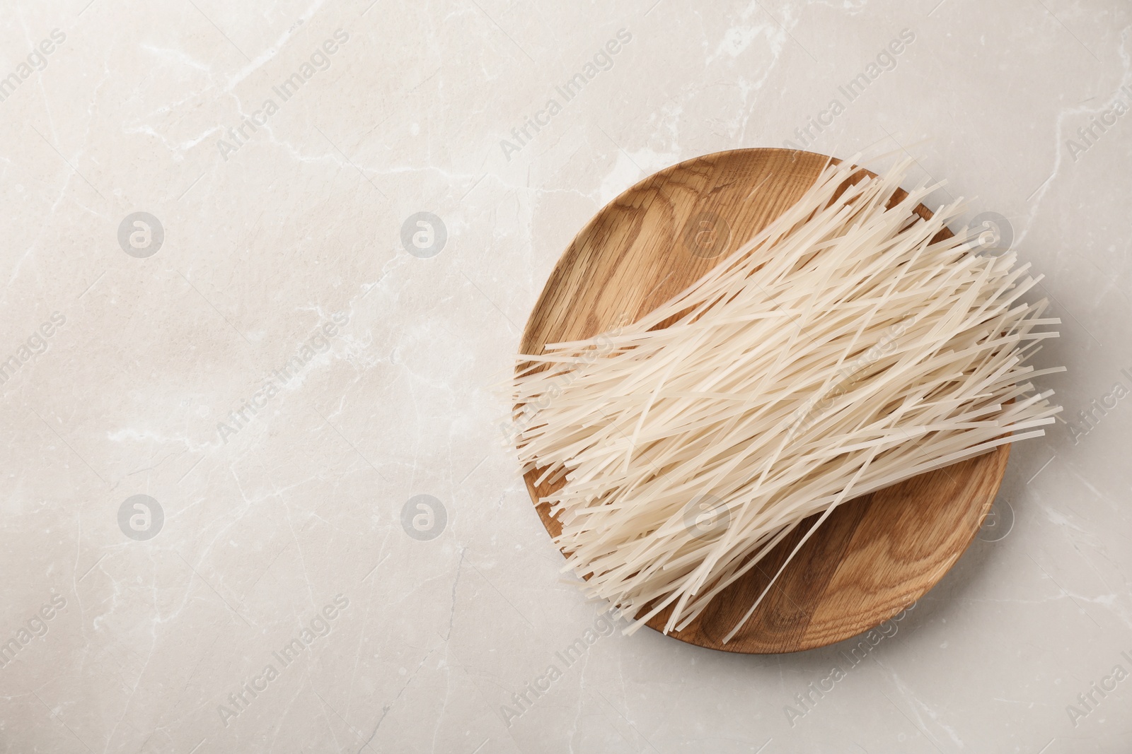 Photo of Plate with raw rice noodles on grey background, top view. Space for text