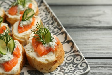 Photo of Tasty canapes with salmon, cucumber, cream cheese and dill on wooden table, closeup