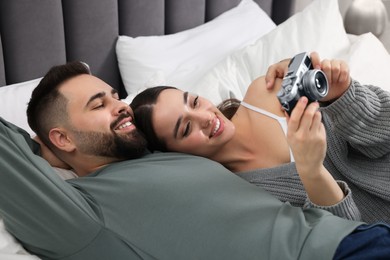 Happy young couple with camera on bed