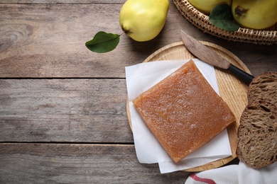 Photo of Delicious quince paste and fresh fruits on wooden table, flat lay. Space for text