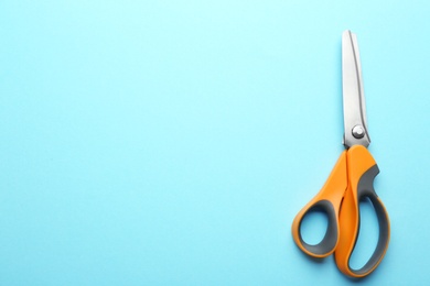 Pair of sharp scissors on color background, top view. Space for text