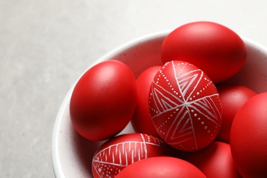 Bowl with red painted Easter eggs on table, closeup