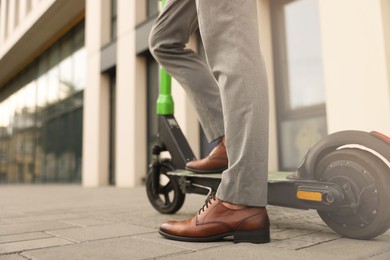 Businessman with modern kick scooter on city street, closeup. Space for text