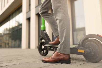 Photo of Businessman with modern kick scooter on city street, closeup. Space for text