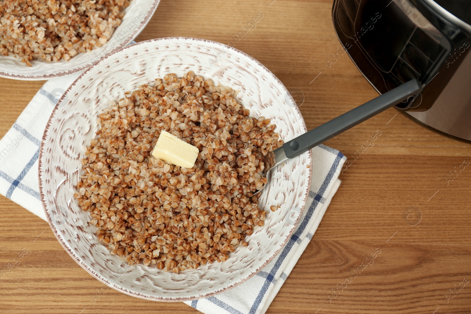 Photo of Delicious buckwheat and modern multi cooker on wooden table, above view