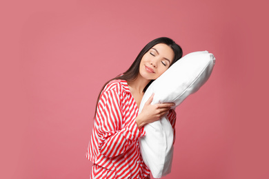 Photo of Beautiful Asian woman with pillow on dusty rose background. Bedtime