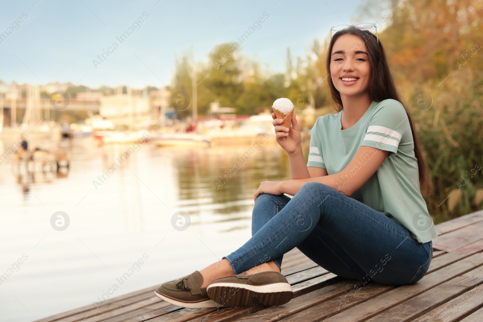 Photo of Happy young woman with delicious ice cream in waffle cone outdoors. Space for text