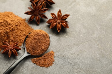 Photo of Spoon with cinnamon powder and star anise on grey table, above view. Space for text