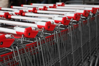 Photo of Many empty metal shopping carts near supermarket outdoors, closeup