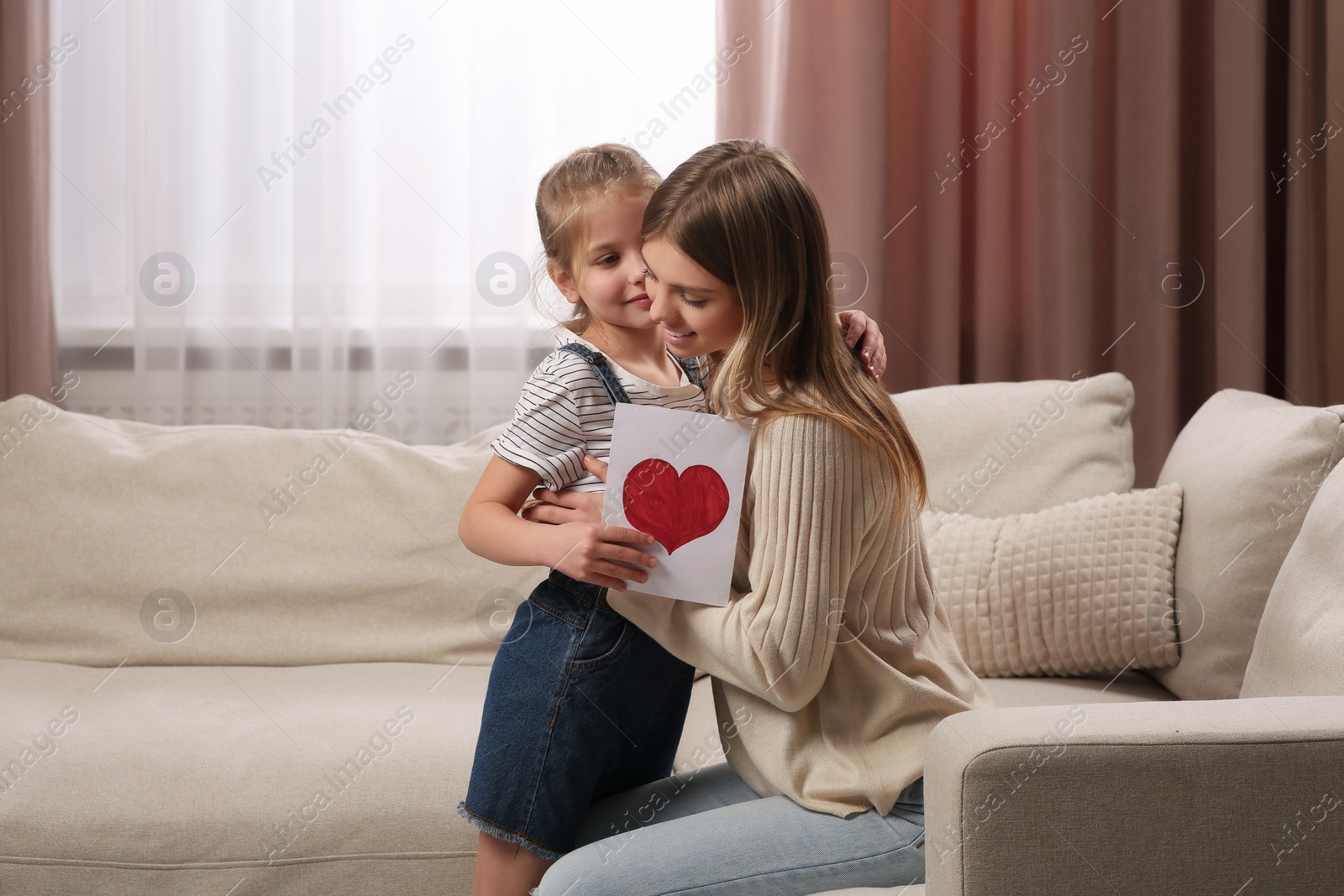 Photo of Little daughter congratulating mom with greeting card at home. Happy Mother's Day