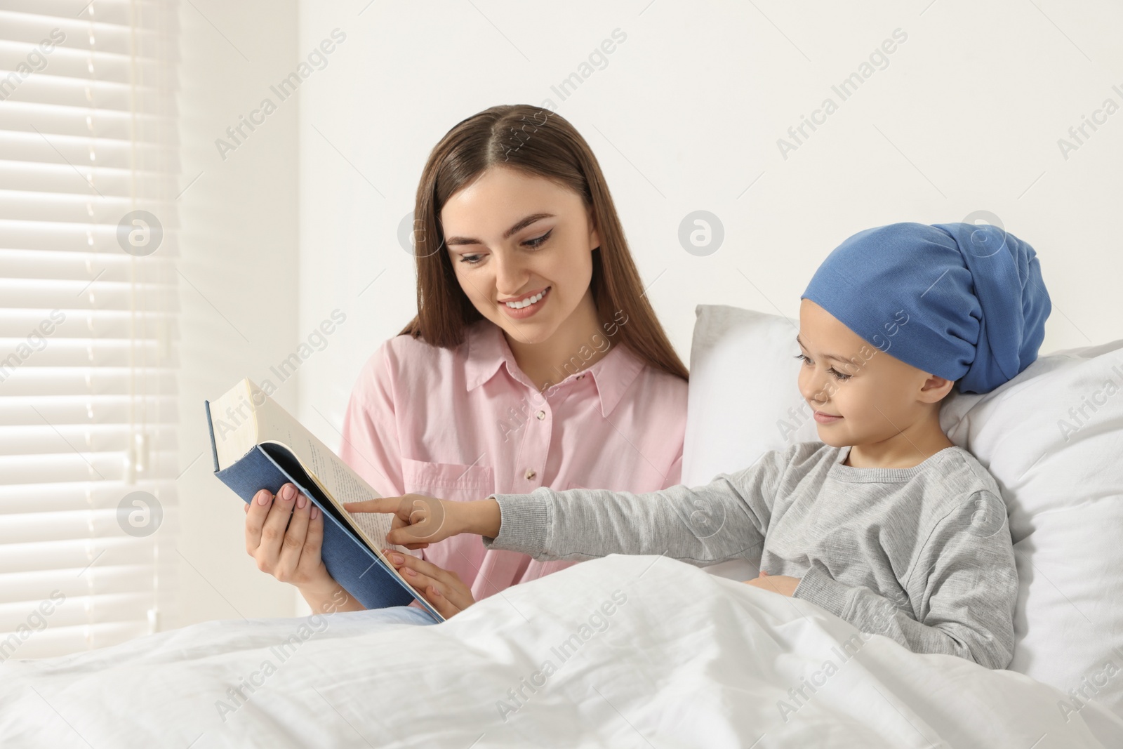 Photo of Childhood cancer. Mother and daughter reading book in hospital