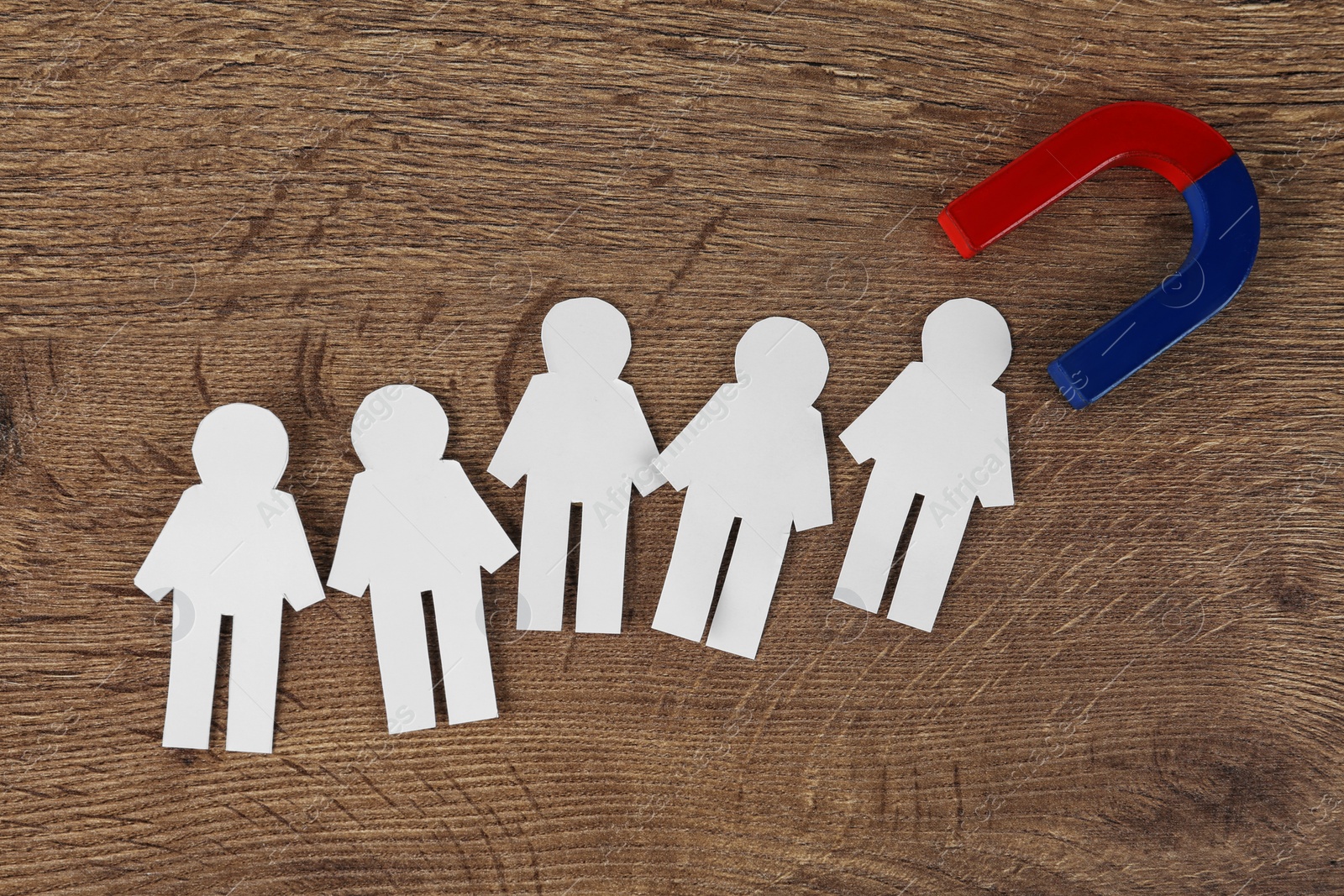 Photo of Magnet and paper people on wooden table, flat lay