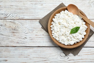 Photo of Delicious cottage cheese with basil on white wooden table, top view. Space for text