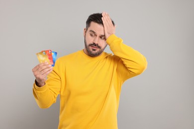 Photo of Confused man with credit cards on grey background. Debt problem