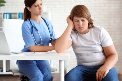 Photo of Emotional overweight boy consulting with doctor in clinic