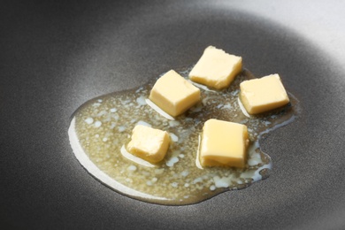 Photo of Pieces of melting butter on frying pan, closeup