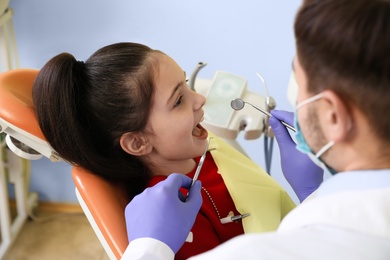 Photo of Professional dentist working with little patient in modern clinic