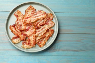 Photo of Delicious fried bacon slices on blue wooden table, top view. Space for text