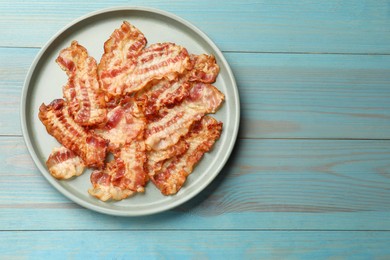 Delicious fried bacon slices on blue wooden table, top view. Space for text