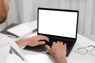 Photo of Man using laptop at white table indoors, closeup