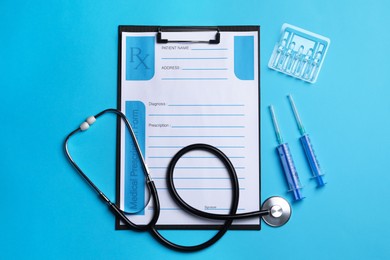 Clipboard with medical prescription form, stethoscope, ampoules and syringes on light blue background, flat lay