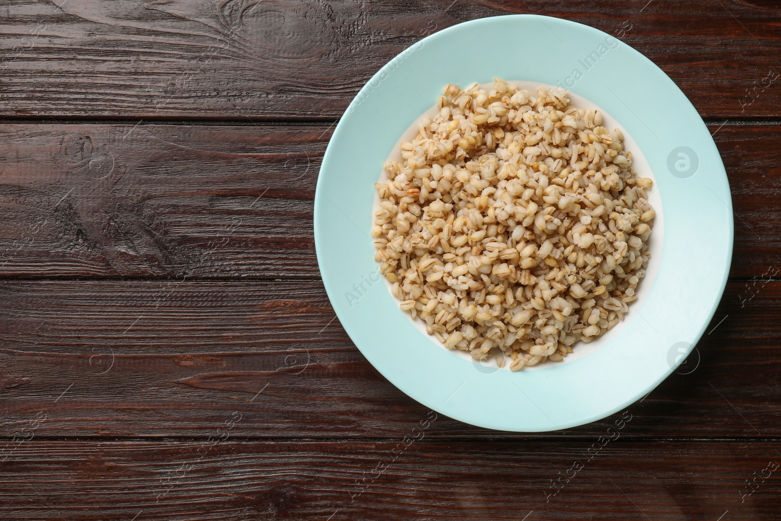 Photo of Delicious pearl barley on wooden table, top view. Space for text